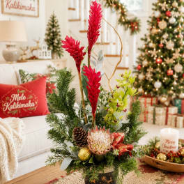 Tall holiday floral arrangement with red blooms, a protea, and pine accents in a vase
