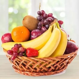 Basket of assorted fruit including bananas, grapes, oranges, kiwi, and strawberries