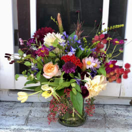 Colorful mixed flower arrangement with roses, dahlias, and tulips in a clear glass vase