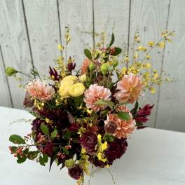 Mixed bouquet with peach, yellow, and burgundy flowers in a vase