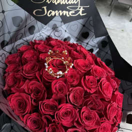 Bouquet of red roses wrapped in black heart-patterned paper with a birthday tag