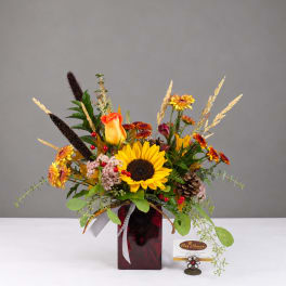Autumn bouquet with sunflowers, roses, and mums in a red glass vase