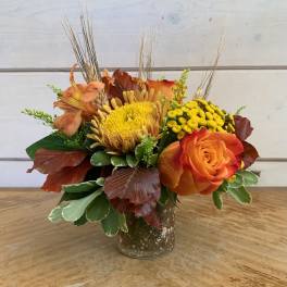 Orange and yellow floral arrangement in a speckled metal vase