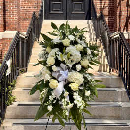 White floral standing spray with roses and lilies on an easel