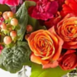 Close-up bouquet of orange and red roses with pink berries