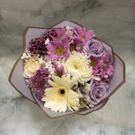 Bouquet of pink and lavender flowers with cream blooms in paper wrap