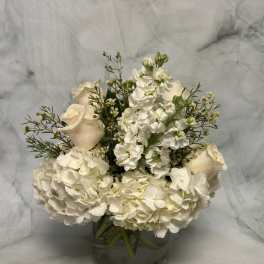 White roses and hydrangeas arranged in a glass vase