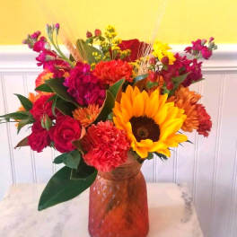 Colorful mixed bouquet in an amber glass vase with a sunflower and roses