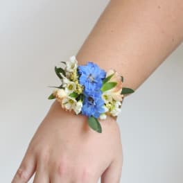 Blue and white floral wrist corsage on a person's wrist
