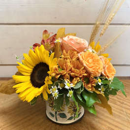 Sunflower and peach rose arrangement in a painted tin container