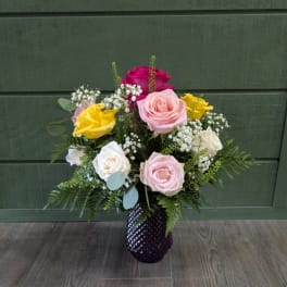 Mixed roses in a purple vase with baby's breath