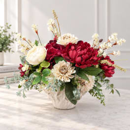 Red and cream floral arrangement in a white vase