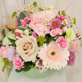 Pastel mixed flower arrangement in a pale green vase
