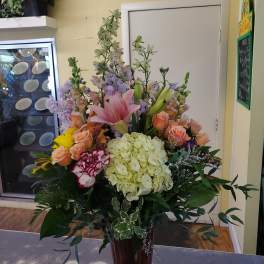Mixed bouquet with pink lilies, peach roses, and pale hydrangeas in a vase