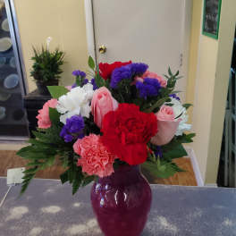 Mixed bouquet of roses and carnations in a purple vase