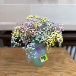 Pastel baby's breath bouquet in a green vase with a purple ribbon