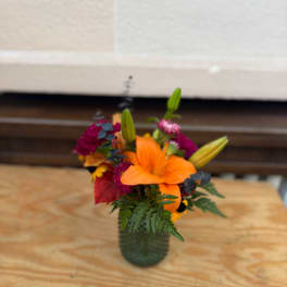 Orange lily bouquet in a green glass vase