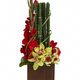 Red flowers with yellow orchids in a wooden vase and bamboo stems