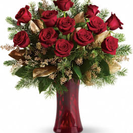 Red roses arranged in a burgundy vase with evergreen accents