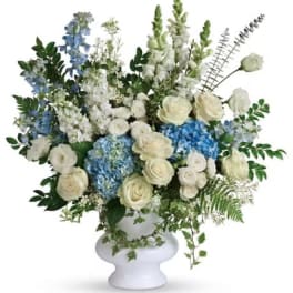 White and blue floral arrangement in a white pedestal vase