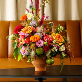 Colorful mixed flower arrangement in a terracotta vase on a table