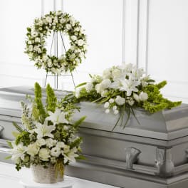 White floral casket spray, wreath, and basket arrangement with lilies and roses