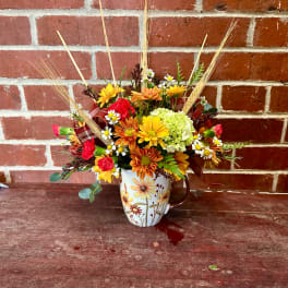 Mixed fall bouquet in a floral mug vase with daisies and mums
