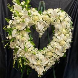 Heart-shaped white floral wreath on a stand with roses and anthuriums