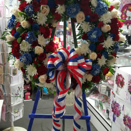 Large floral wreath with red, white, and blue flowers on an easel