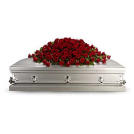 Large spray of red roses draped over a closed silver casket.