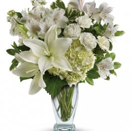 White lilies, hydrangea, and alstroemeria in a clear glass vase