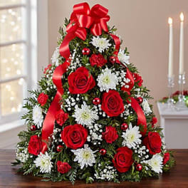 Christmas tree-shaped floral arrangement with red roses, white daisies, and a red bow