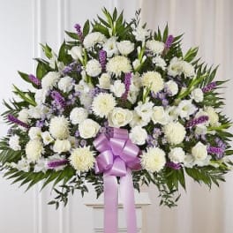 Large white funeral spray with purple accents and a lavender ribbon
