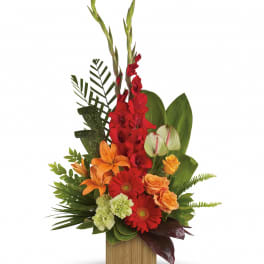 Tropical bouquet with red gladiolus, orange lilies, and gerbera daisies in a wooden container