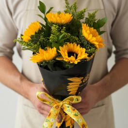 Bouquet of yellow sunflowers wrapped in black paper with a yellow ribbon
