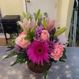 Mixed bouquet with pink lilies, roses, gerbera daisies, and carnations in a round vase