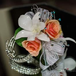 Small floral wrist corsage with peach roses and a white orchid on silver ribbon
