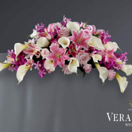 Pink lilies, white calla lilies, and roses arranged on a gray tablecloth