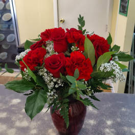 Red roses and carnations arranged in a burgundy vase
