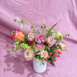 Mixed bouquet in a white textured vase with pink, peach, and white blooms