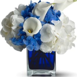 Blue and white floral arrangement in a square glass vase