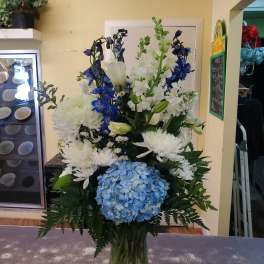 Tall blue and white floral arrangement in a clear vase