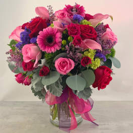 Bouquet of pink and red roses with gerbera daisies in a glass vase
