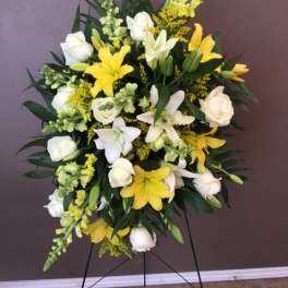 Standing floral spray with white roses and yellow lilies on a metal easel