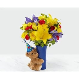 Bright mixed bouquet in a blue vase with a teddy bear attached