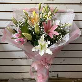 Bouquet of pink, white, and yellow lilies wrapped in pink paper
