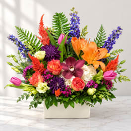 Colorful mixed flower arrangement in a white rectangular vase