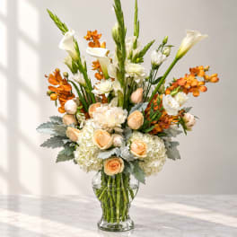 Tall bouquet of white and peach flowers in a clear glass vase