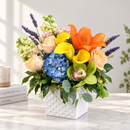 Colorful bouquet with lilies, roses, hydrangea, and calla lilies in a white vase