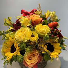 Basket arrangement with yellow roses, sunflowers, and orange blooms